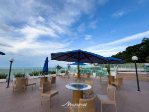 eine Terrasse mit Tischen, Stühlen und einem Sonnenschirm in der Unterkunft Blue Sunset in João Pessoa