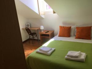 een slaapkamer met een groen bed met 2 handdoeken erop bij Alojamento Local Duarte's in Coimbra