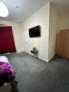 a bedroom with a bed and a tv on the wall at Elm Vale Lodge in Liverpool