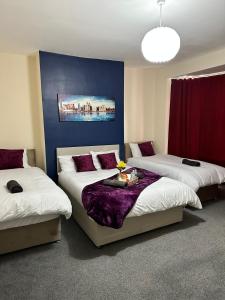 a room with three beds and a blue wall at Elm Vale Lodge in Liverpool