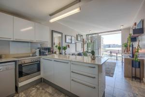 a kitchen with white cabinets and a large window at Aircon Parking Washer Modern Ornate Waterfront in Cape Town