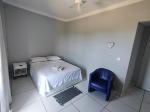 sypialnia z łóżkiem i niebieskim krzesłem w obiekcie Ed Bertholi - Frente ao mar com garagem w mieście Serra