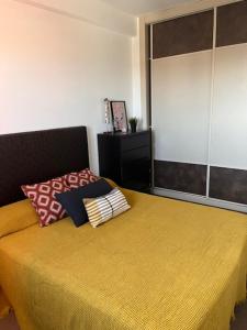 Un dormitorio con una cama amarilla con almohadas. en Apartamento con vistas en Roquetas de Mar