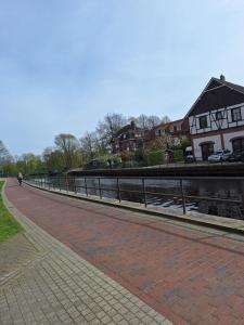a brick road next to a river with houses at Eleni in Emden