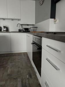 a kitchen with white cabinets and a wooden floor at APARTAMENTY CENTRUM in Kostrzyn nad Odrą