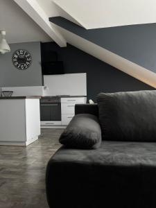 a living room with a couch and a clock on the wall at APARTAMENTY CENTRUM in Kostrzyn nad Odrą