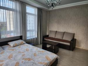 a bedroom with a bed and a bench and windows at Apartment KG in Bishkek +9 photos