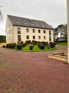 a building with a lot of bushes in front of it at Appartement Brise Marine in Grandcamp-Maisy