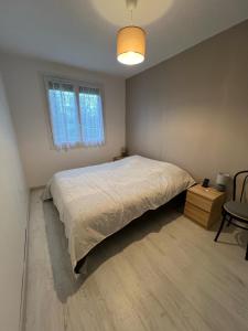 a bedroom with a bed and a table and a window at Appartement Brise Marine in Grandcamp-Maisy