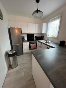 a kitchen with white cabinets and a stainless steel refrigerator at Appartement Brise Marine in Grandcamp-Maisy +7 photos