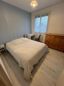 a bedroom with a bed and a dresser and a window at Appartement Brise Marine in Grandcamp-Maisy