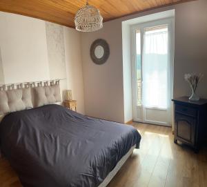 una camera da letto con un letto grande e una finestra di L’Hacienda, maison de caractère a Saint-Martin-de-Valamas