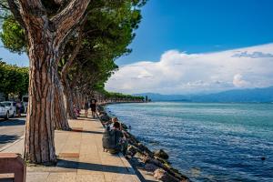 mensen op een stoep naast het water bij Al Bivio Peschiera - Italian Homing in Peschiera del Garda