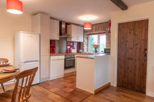 una cucina con elettrodomestici bianchi, tavolo e tavolo di Dunkery Cottage Wheddon Cross a Minehead
