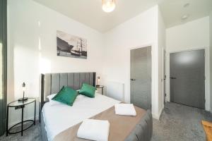 a bedroom with a large white bed with green pillows at Dockside in Dundee