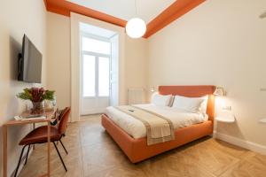Dormitorio con cama, escritorio y TV en Pignasuite en Nápoles