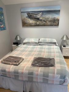 uma cama com um cobertor xadrez e uma pintura na parede em Beach Cottage em Berwick-Upon-Tweed