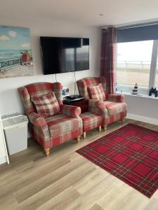 uma sala de estar com 2 cadeiras e uma televisão de ecrã plano em Beach Cottage em Berwick-Upon-Tweed