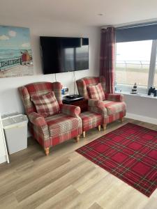 a living room with two chairs and a flat screen tv at Beach Cottage in Berwick-Upon-Tweed