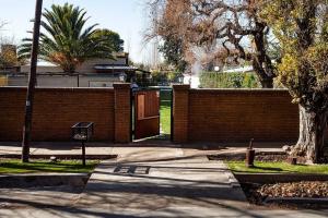 a brick fence with a gate and a tree at Casa Wineland Logde West 4Pax - by Inside in Ciudad Lujan de Cuyo