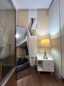 a bedroom with a mirror and a table with a lamp at Azure Staycation in Manila