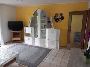 a living room with a white cabinet and a tv at Widmann‘s Ferienquartier in Wiehl