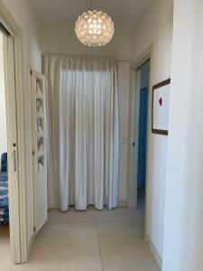 - une chambre avec un rideau blanc et un lustre dans l'établissement Attico, à Viareggio