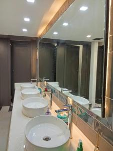 a bathroom with three sinks and a large mirror at OSTELO Mumbai Airport Hostel in Mumbai