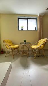 ムンバイにあるOSTELO Mumbai Airport Hostelの椅子2脚、テーブル、窓が備わる客室です。