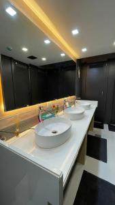 three sinks in a bathroom with black cabinets at OSTELO Mumbai Airport Hostel in Mumbai