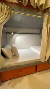 ein kleines Bett in einem Zimmer mit Etagenbett in der Unterkunft OSTELO Mumbai Airport Hostel in Mumbai