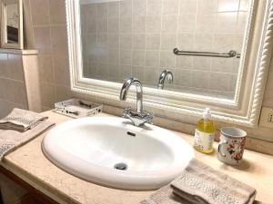 een badkamer met een witte wastafel en een spiegel bij Casa Malù Suvereto Antica Dimora with two bedrooms in Suvereto