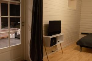 a television on a stand in a room with a window at Aurora panorama in Laksvatn