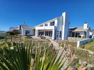 a white house with a palm plant in front of it at Mustique-Beachfront bliss in St. Helena Bay