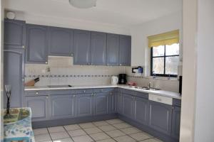 a kitchen with blue cabinets and a sink at Buitenplaats 144 in Callantsoog