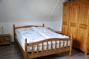 a wooden bed in a bedroom with a wooden cabinet at Buitenplaats 144 in Callantsoog