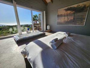 a bedroom with a large bed and a large window at Mustique-Beachfront bliss in St. Helena Bay