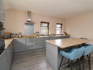 eine große Küche mit einer Holztheke und blauen Barhockern in der Unterkunft Heritage in Carmarthen