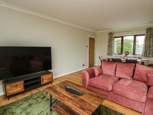 a living room with a red couch and a flat screen tv at The Oaks in Carmarthen