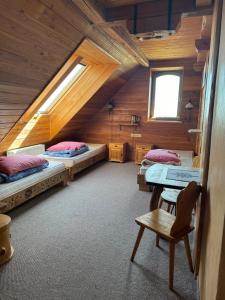 a attic room with two beds and a chair at Krynicka Koliba na Jaworzynie Krynickiej in Krynica Zdrój