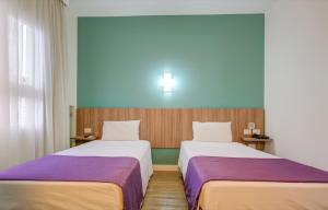 duas camas num quarto de hotel com lençóis roxos em Go Inn Cambuí Campinas em Campinas