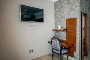 Zimmer mit einem Stuhl und einem TV an der Wand in der Unterkunft Lujoso departamento en Leon in León