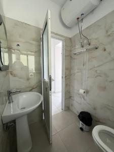 bagno bianco con lavandino e doccia di Villa Mirjan a Sarandë