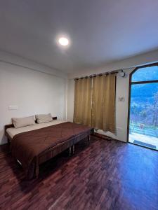 una camera da letto con un letto e una grande finestra di Nomadic Den Manali a Manāli
