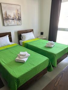 two beds in a room with green sheets and towels at St Gaetan Accomodation APT 7 B 