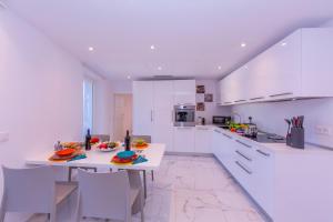 cocina con armarios blancos, mesa y sillas en Yellow View Apartment - Happy Rentals en Ronco s/Ascona - Porto Ronco