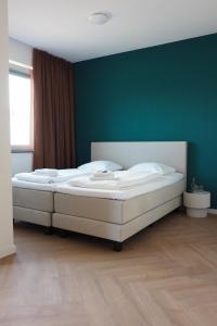 a bedroom with two beds with a green wall at Hotel 't Vertrek in Boxmeer
