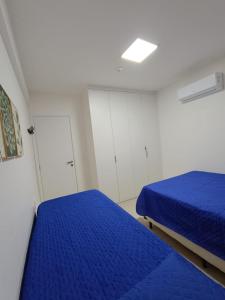 1 dormitorio con 2 camas azules y armarios blancos en Lindo flat, na beira do lago, na melhor praia da Bahia en Guarajuba