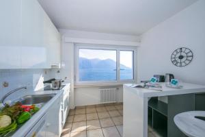 eine weiße Küche mit einem Waschbecken und einem Fenster in der Unterkunft Bellevue Apartment - Happy Rentals in Ronco sopra Ascona