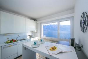 eine weiße Küche mit Blick auf das Wasser in der Unterkunft Bellevue Apartment - Happy Rentals in Ronco sopra Ascona